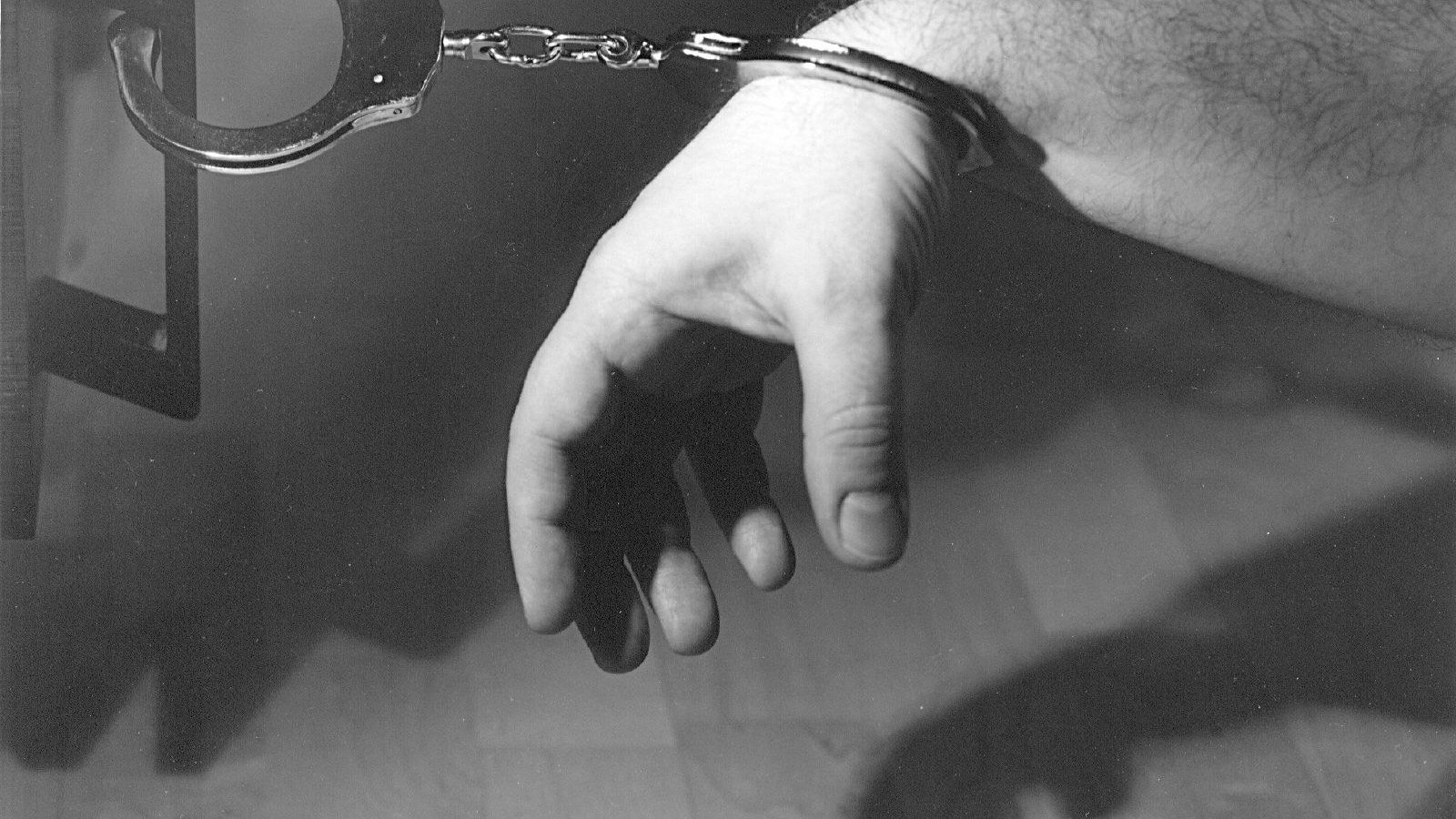 Esposas de acero sobre fondo neutro, símbolo de la detención del presunto hacker y de su cooperación con el FBI