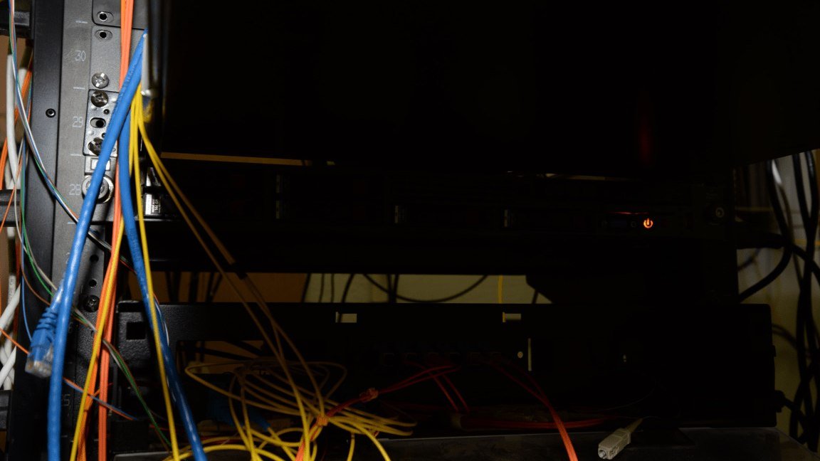 Rack de servidores en un centro de datos con un indicador luminico encendido y cables de red, en penumbra